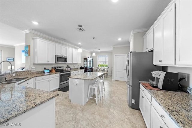 kitchen with sink, a center island, a kitchen breakfast bar, pendant lighting, and appliances with stainless steel finishes