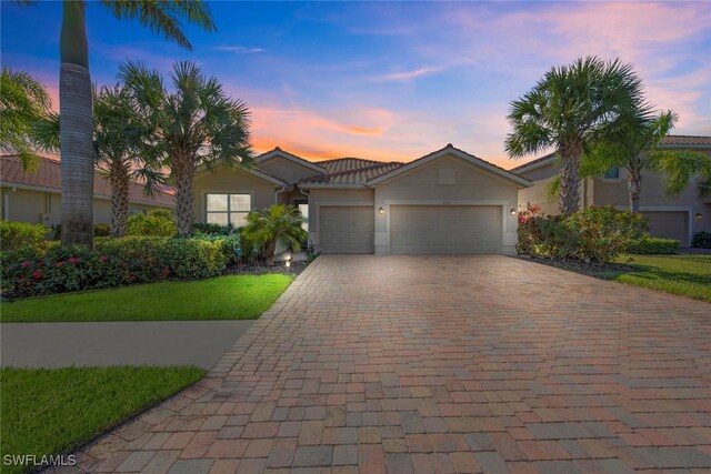 view of front of home with an attached garage, a tiled roof, decorative driveway, and stucco siding