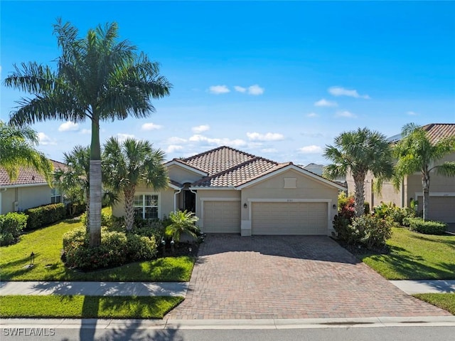 view of front of home with decorative driveway, a tile roof, stucco siding, a front yard, and a garage