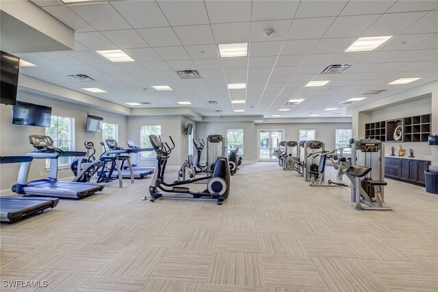 gym featuring a paneled ceiling and light colored carpet