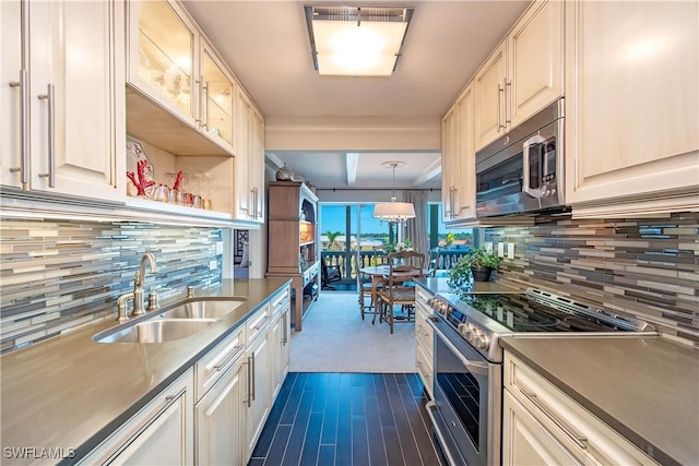 kitchen with decorative backsplash, appliances with stainless steel finishes, sink, white cabinets, and hanging light fixtures