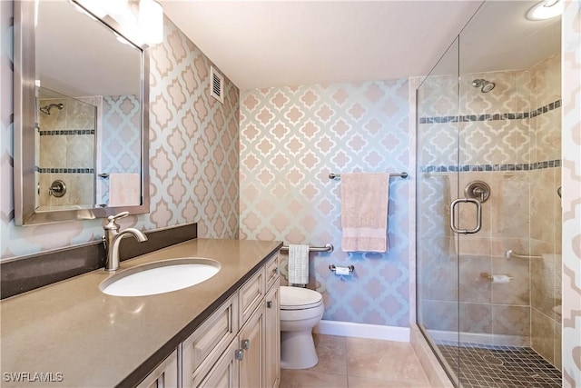 bathroom featuring tile patterned flooring, vanity, a shower with shower door, and toilet