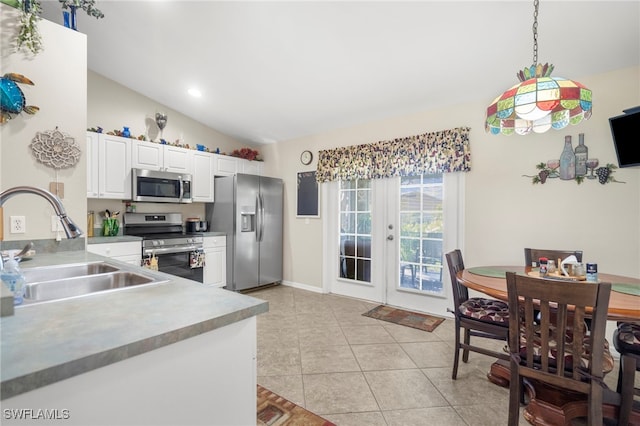 kitchen featuring sink, pendant lighting, lofted ceiling, white cabinets, and appliances with stainless steel finishes