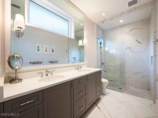 bathroom with a tile shower, vanity, and toilet