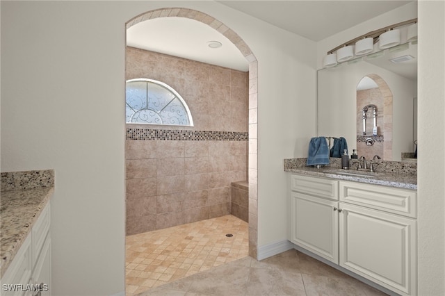 bathroom featuring tile patterned floors, vanity, and a tile shower