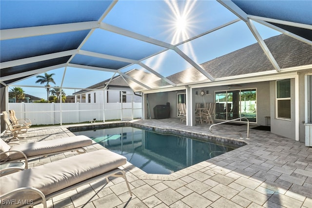 view of swimming pool with glass enclosure, ceiling fan, and a patio