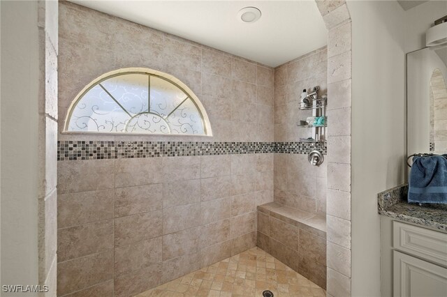 bathroom with a tile shower and vanity