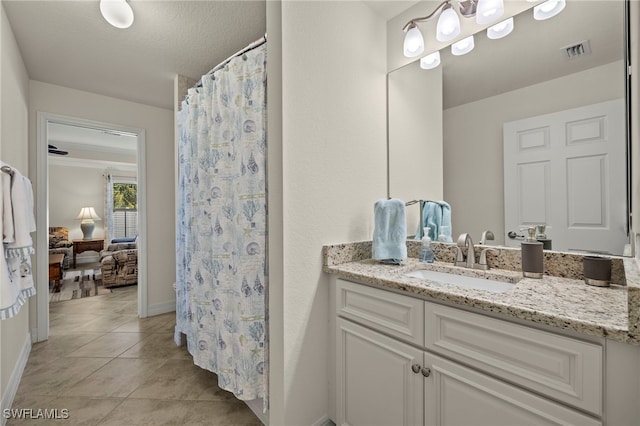 bathroom featuring tile patterned flooring, vanity, a textured ceiling, and walk in shower