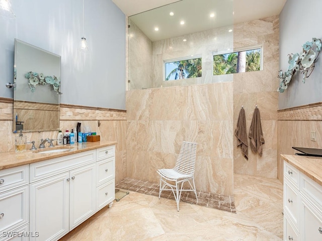 bathroom featuring a shower, vanity, and tile walls