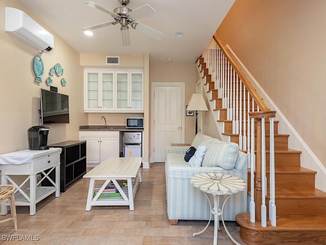 living room with ceiling fan, sink, and a wall unit AC