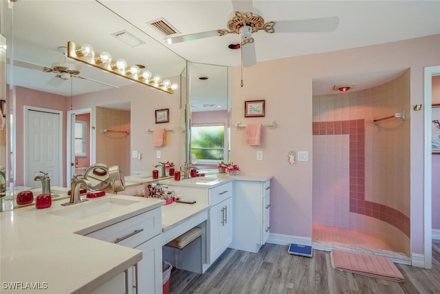 bathroom with tiled shower, ceiling fan, vanity, and hardwood / wood-style flooring