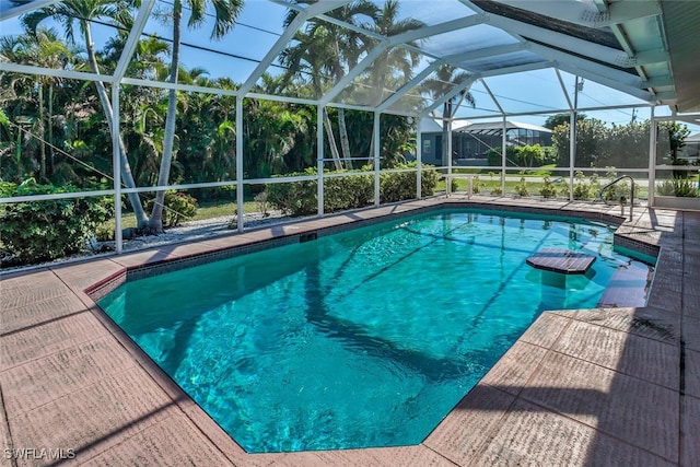 view of pool with glass enclosure and a patio area