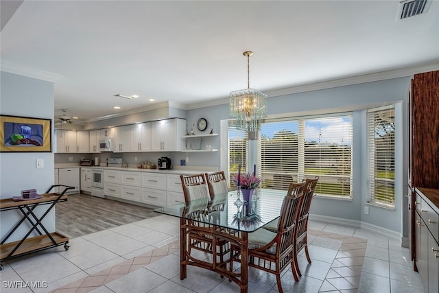 tiled dining space featuring ceiling fan with notable chandelier and crown molding