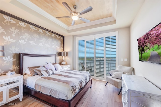 bedroom featuring access to exterior, light wood-type flooring, a tray ceiling, and ceiling fan