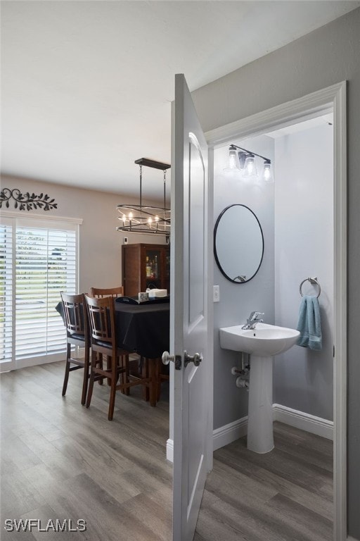 bathroom with hardwood / wood-style floors and an inviting chandelier