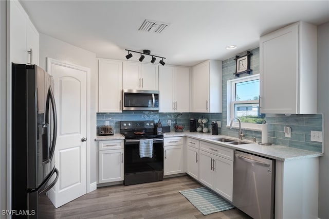 kitchen with sink, light hardwood / wood-style floors, decorative backsplash, white cabinets, and appliances with stainless steel finishes