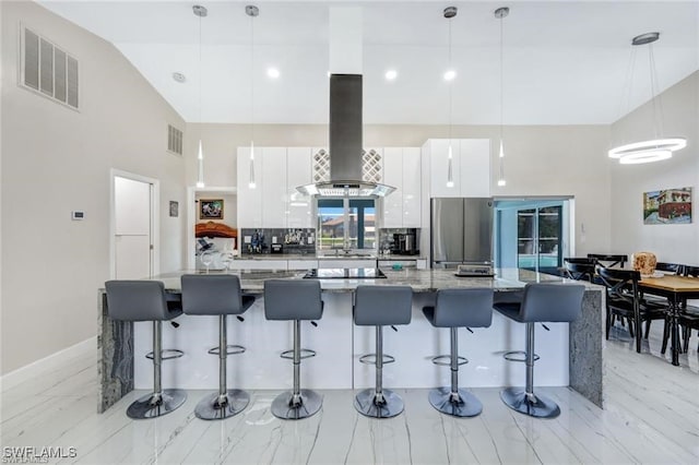 kitchen with pendant lighting, white cabinets, dark stone countertops, island range hood, and a breakfast bar area