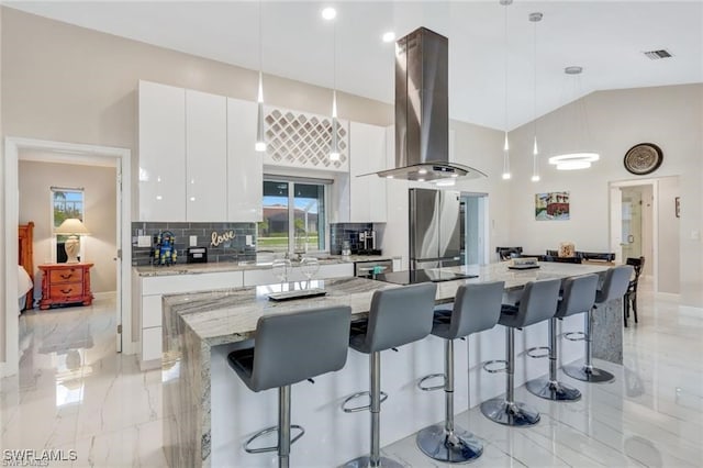 kitchen with island range hood, a spacious island, pendant lighting, white cabinetry, and stainless steel refrigerator