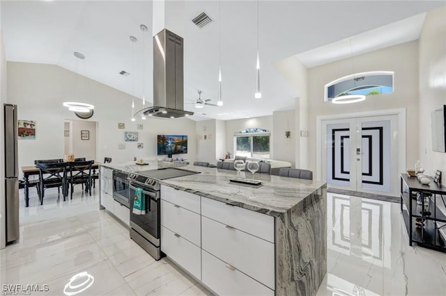 kitchen featuring high vaulted ceiling, stainless steel electric stove, hanging light fixtures, island range hood, and white cabinetry