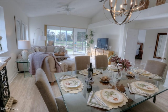 dining room with ceiling fan with notable chandelier, light wood-type flooring, and lofted ceiling