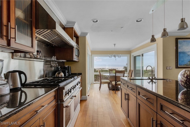 kitchen featuring dark stone counters, crown molding, light hardwood / wood-style flooring, high end stainless steel range, and hanging light fixtures