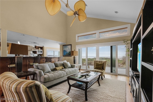 living room with crown molding, light hardwood / wood-style flooring, a towering ceiling, and a healthy amount of sunlight