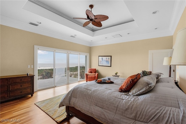 bedroom with access to exterior, a tray ceiling, ceiling fan, crown molding, and light hardwood / wood-style floors