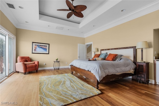 bedroom with access to exterior, ornamental molding, a tray ceiling, ceiling fan, and hardwood / wood-style flooring