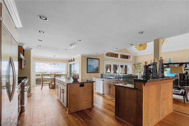 kitchen featuring pendant lighting, a center island with sink, hardwood / wood-style flooring, kitchen peninsula, and stainless steel appliances