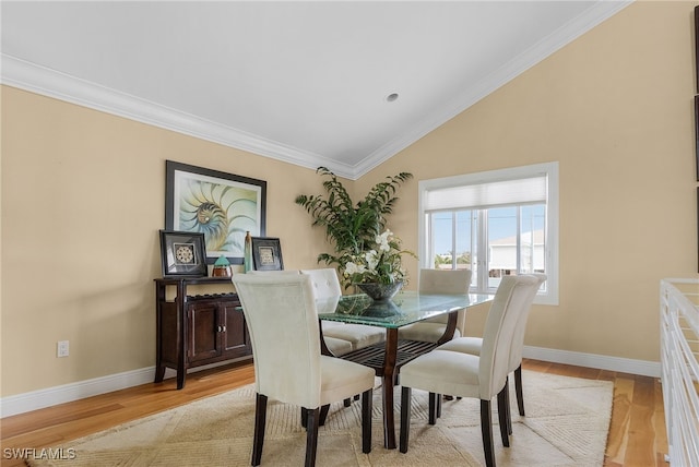 dining area featuring crown molding, lofted ceiling, and light wood-type flooring