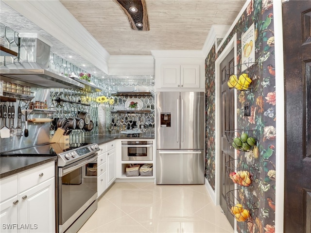 kitchen featuring wall chimney exhaust hood, appliances with stainless steel finishes, tasteful backsplash, light tile patterned flooring, and white cabinetry