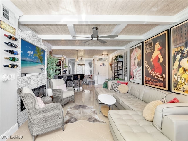 tiled living room featuring beam ceiling, a stone fireplace, ceiling fan, and wooden ceiling