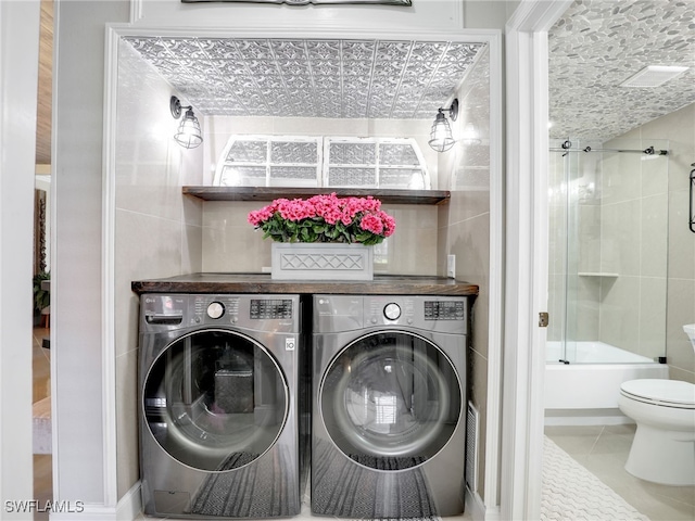 clothes washing area with independent washer and dryer and tile patterned floors