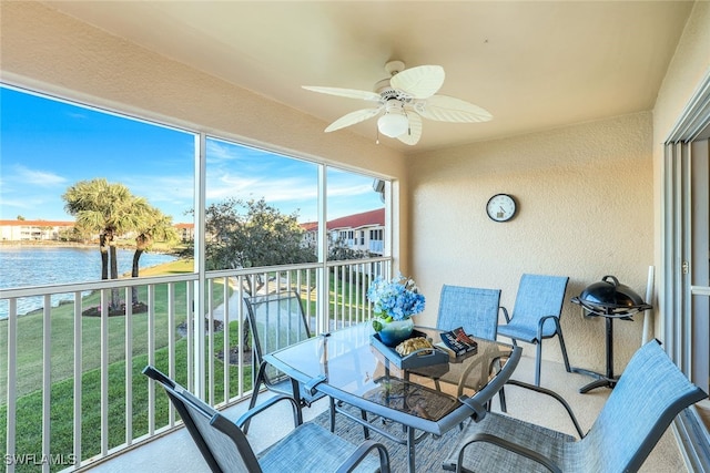 sunroom / solarium featuring ceiling fan and a water view