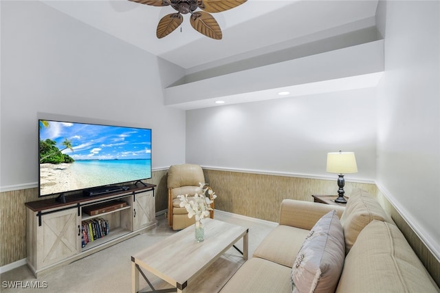 carpeted living room with ceiling fan and wooden walls