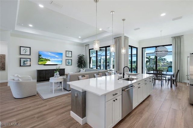 kitchen featuring a kitchen island with sink, pendant lighting, a chandelier, light hardwood / wood-style floors, and white cabinetry