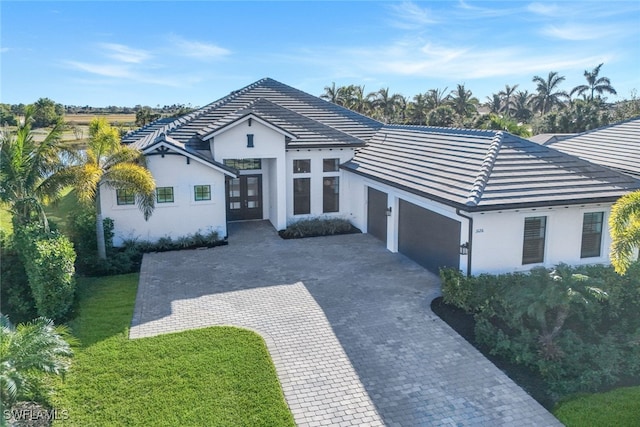 ranch-style house featuring french doors, a front yard, and a garage