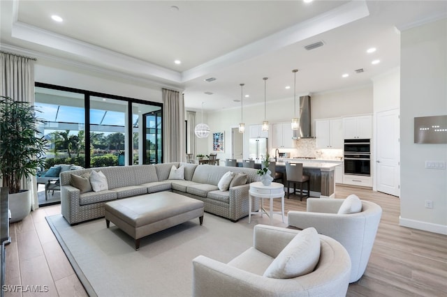 living room featuring a raised ceiling, light hardwood / wood-style floors, and ornamental molding