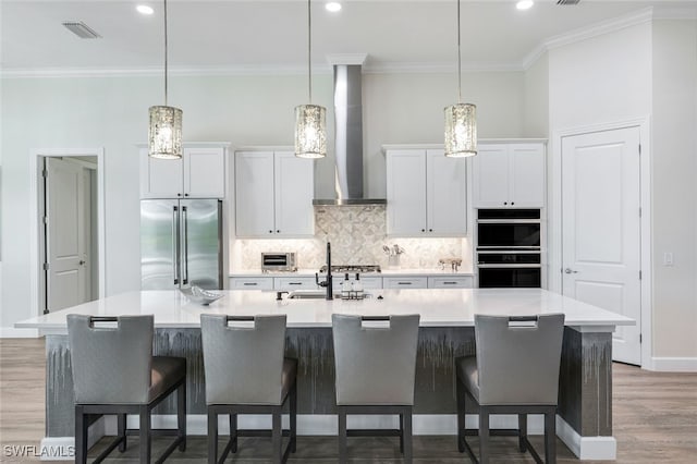 kitchen featuring hanging light fixtures, high end fridge, a spacious island, and wall chimney exhaust hood