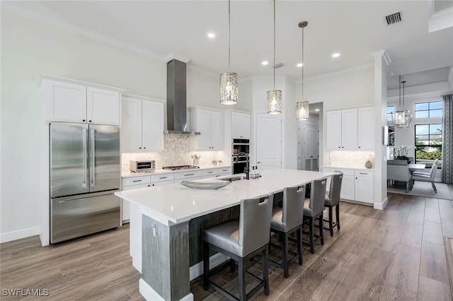 3126 Heather Glen Ct, Naples, FL 34114 - kitchen with stainless steel appliances, wall chimney exhaust hood, a chandelier, crown molding, and decorative backsplash