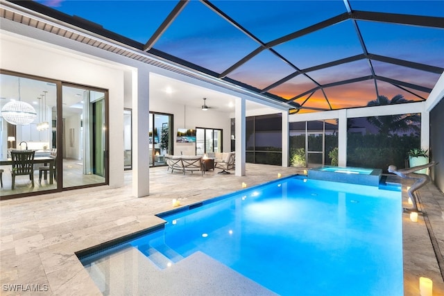 pool at dusk with glass enclosure, ceiling fan, an outdoor living space, a patio area, and an in ground hot tub