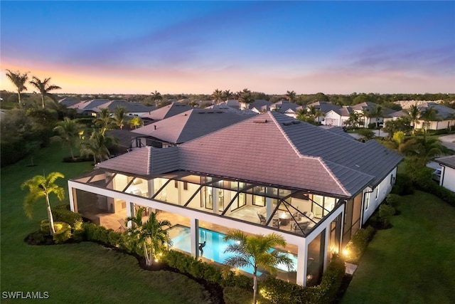 3126 Heather Glen Ct, Naples, FL 34114 - back of house at dusk featuring a residential view, an outdoor pool, a yard, a patio, and stucco siding