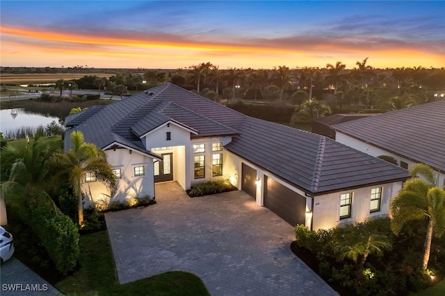 3126 Heather Glen Ct, Naples, FL 34114 - view of front facade featuring an attached garage, decorative driveway, stucco siding, and a water view
