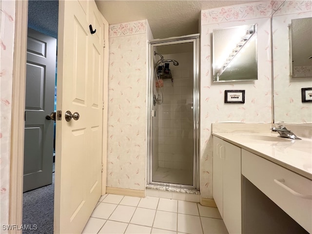 bathroom featuring tile patterned flooring, vanity, a shower with shower door, and a textured ceiling