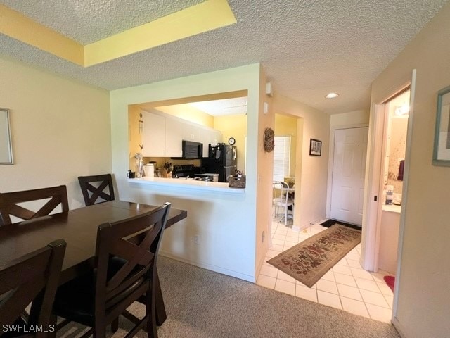 carpeted dining area with a textured ceiling