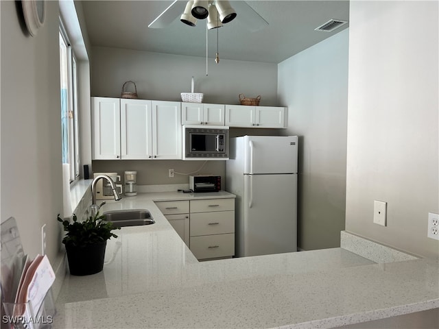 kitchen featuring light stone counters, sink, white refrigerator, white cabinets, and stainless steel microwave