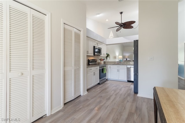 kitchen with ceiling fan, white cabinets, stainless steel appliances, and light wood-type flooring