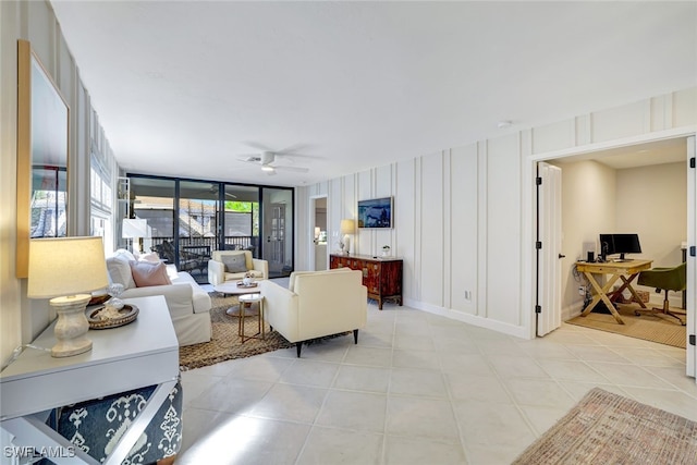 tiled living room featuring ceiling fan and expansive windows