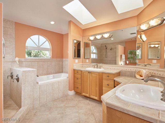 bathroom featuring tile patterned flooring, vanity, shower with separate bathtub, and a skylight