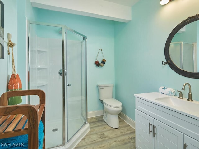 bathroom featuring wood-type flooring, vanity, toilet, and a shower with door